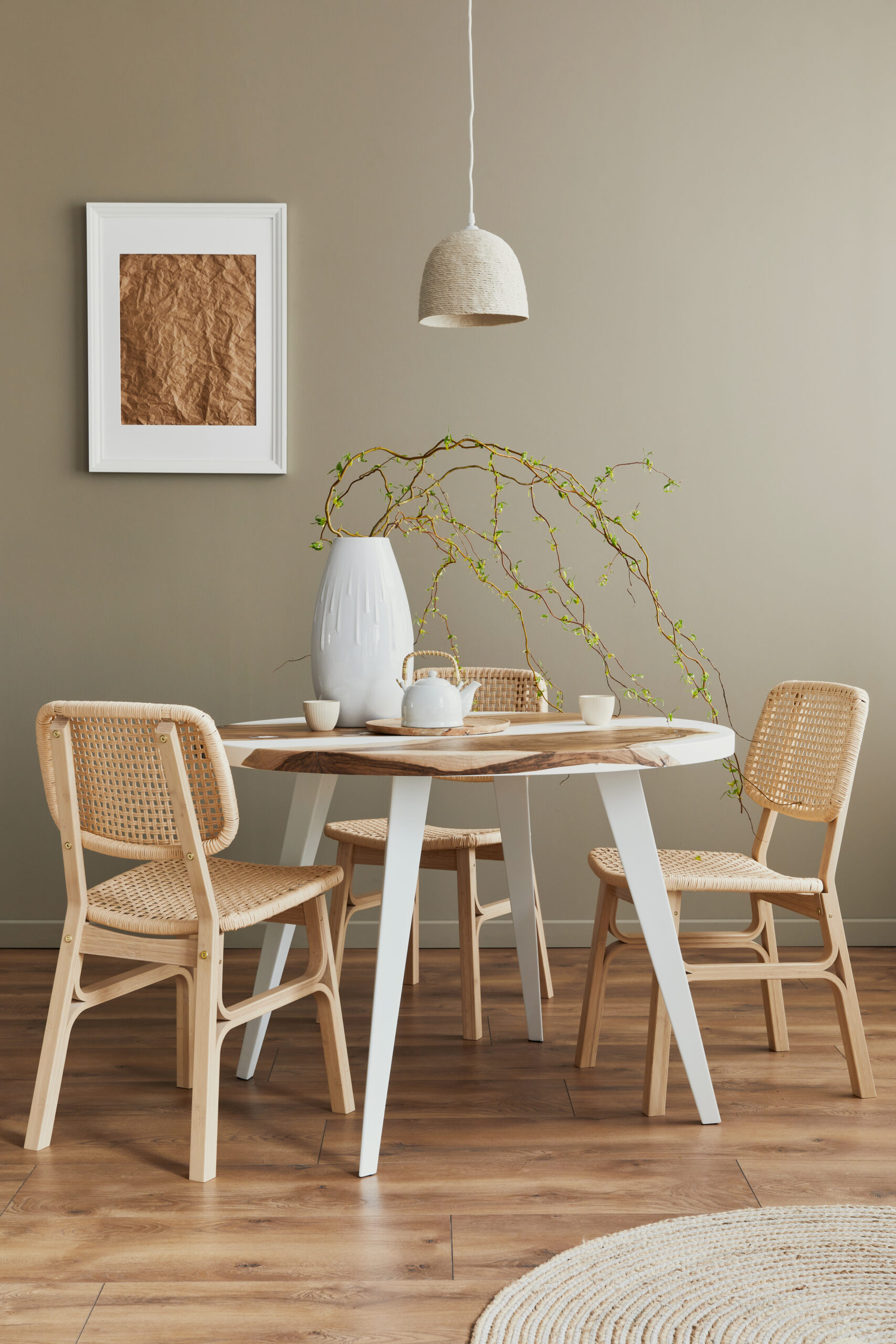 Stylish interior of dining room at cozy home with white mock up poster frame, design chairs, family table, teapot, cups, decoration and elegant personal accessories in modern home decor. Template.